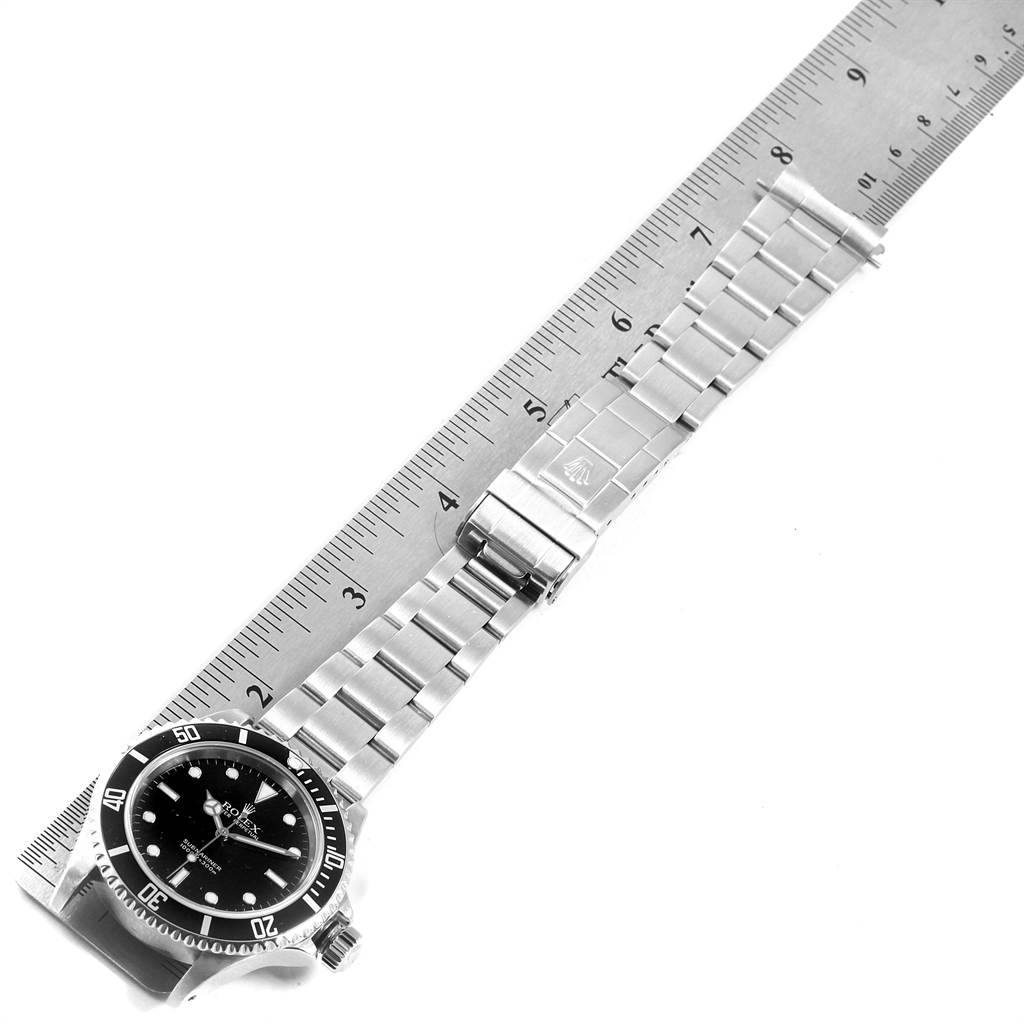 The Rolex Submariner 14060 Men's Stainless Steel Black Dial 14060 Men's Stainless Steel Black Dial watch is shown from a top-down angle, displaying the dial, bezel, and metal bracelet next to a ruler for scale.