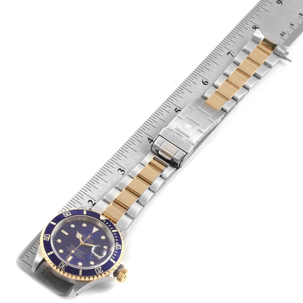 This image shows a Rolex Submariner 16613 Men's Steel and Gold (two tone) Blue Dial 16613 Men's Steel and Gold (two tone) Blue Dial laying flat, with the face, bezel, crown, band, and clasp visible, measured against a ruler.