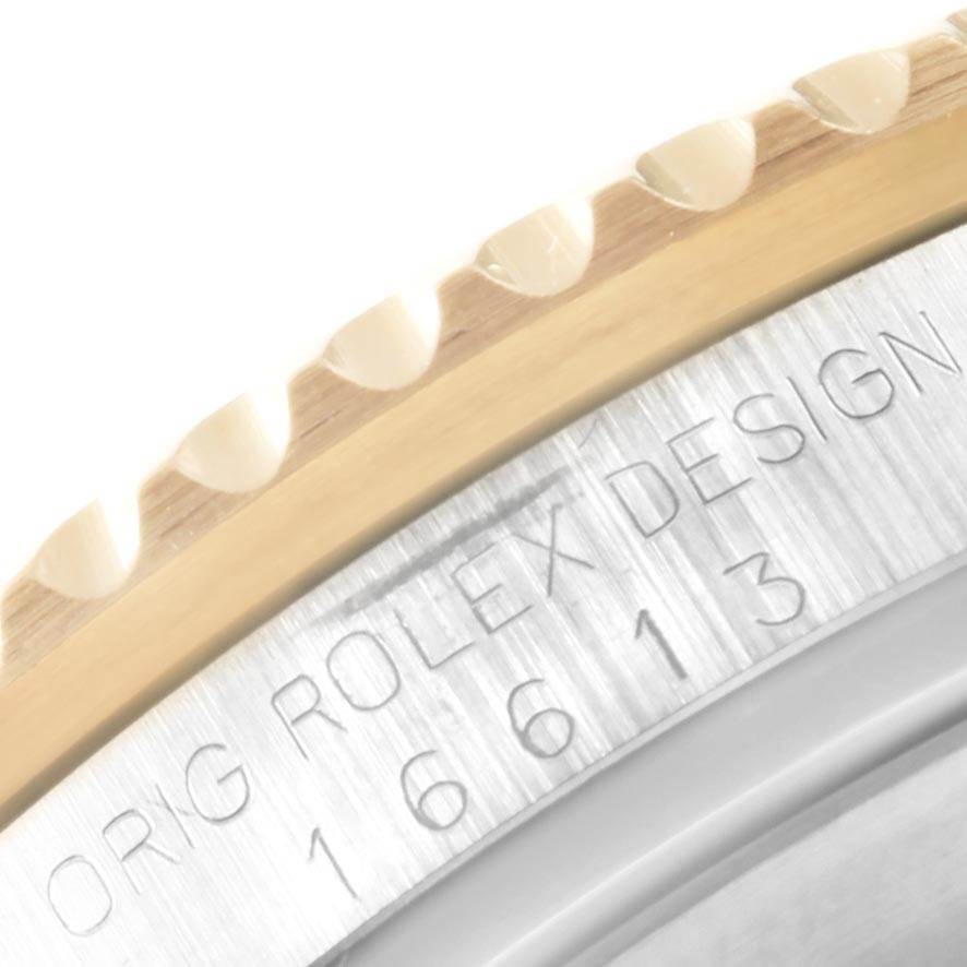 The image shows a close-up of the edge of the bezel and engraved text on the back of a Rolex Submariner 16613 Men's Steel and Gold (two tone) Blue Dial 16613 Men's Steel and Gold (two tone) Blue Dial watch.