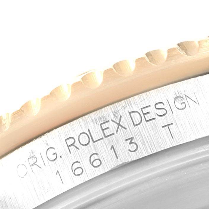 This close-up image shows the engraved model number "16613 T" and "ORIG. ROLEX DESIGN" on the bezel and case of a Rolex Submariner 16613 Men's Steel and Gold (two tone) Black Dial 16613 Men's Steel and Gold (two tone) Black Dial.