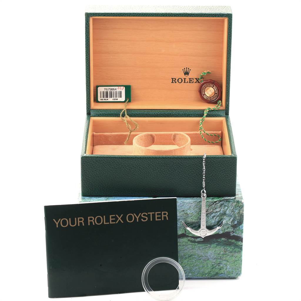 The image displays a Rolex Submariner 16618 Men
s Yellow Gold Black Dial 16618 Men
s Yellow Gold Black Dial watch box, with an anchor tag, booklet, warranty card, and a bezel protector.