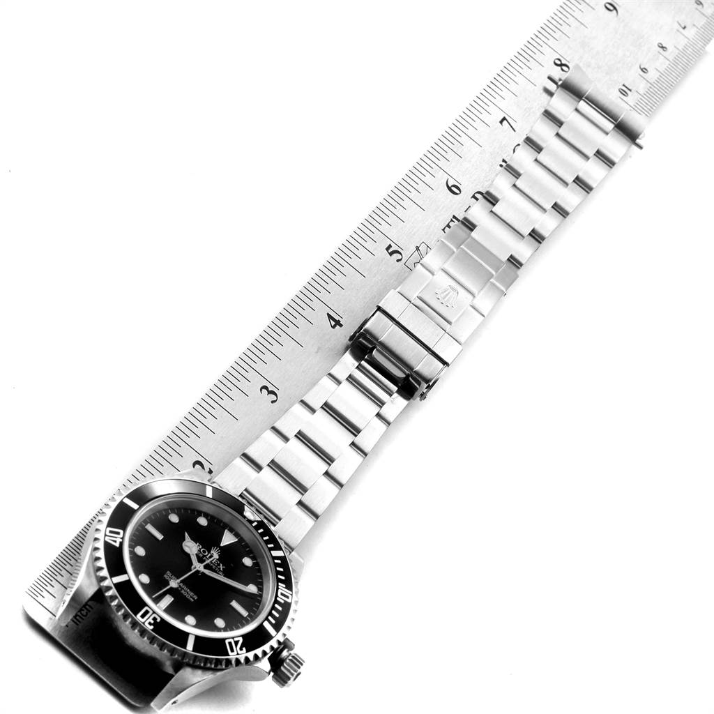The image shows a Rolex Submariner 14060 Men
s Stainless Steel Black Dial 14060 Men
s Stainless Steel Black Dial watch face and bracelet aligned with a ruler.