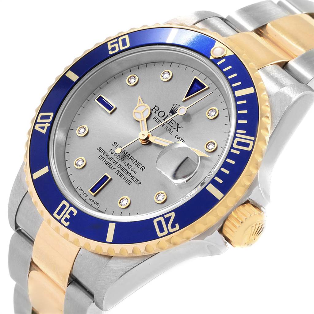 The image shows a Rolex Submariner 16613 Men
s Steel and Gold (two tone) Grey Dial 16613 Men
s Steel and Gold (two tone) Grey Dial watch at an angled close-up, highlighting the bezel, dial, crown, and part of the strap.