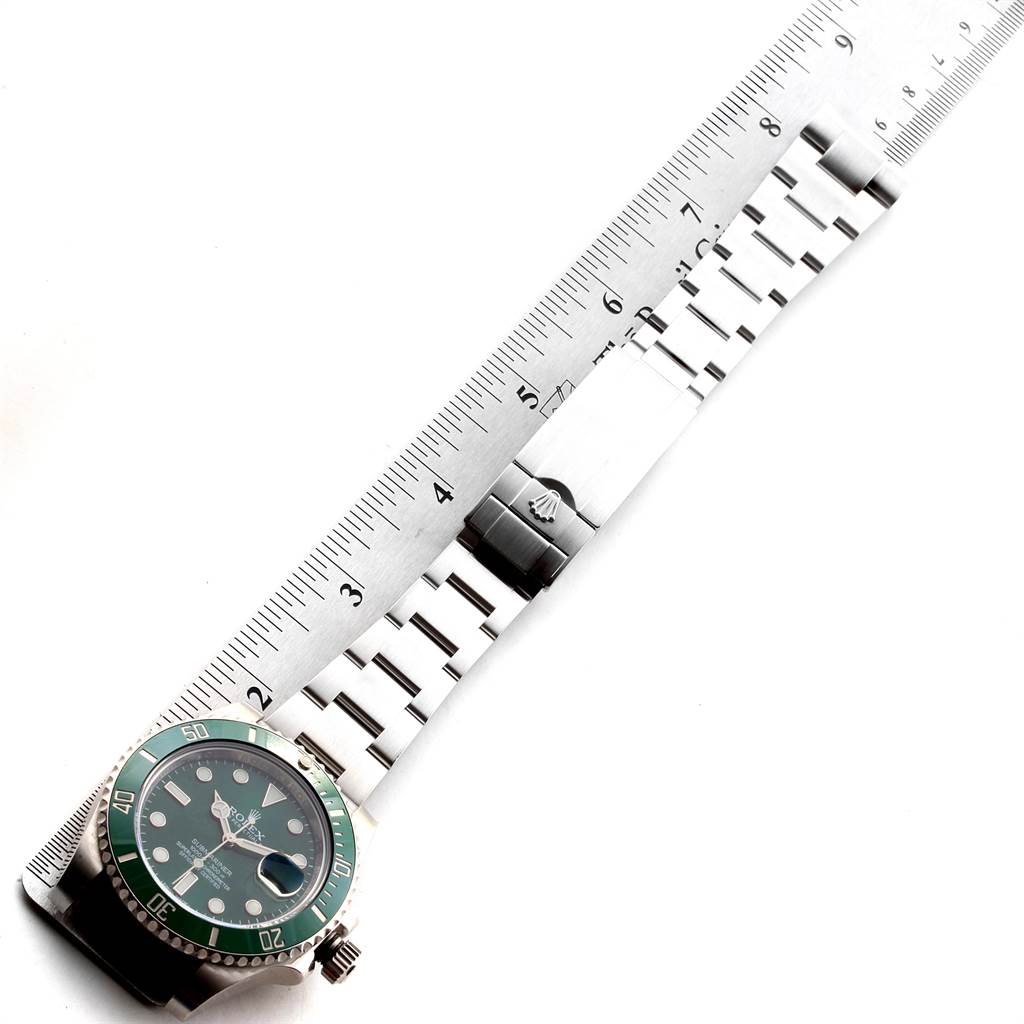 This image shows a top view of a Rolex Submariner 116610LV Men
s Stainless Steel Green Dial 116610LV Men
s Stainless Steel Green Dial watch with a green bezel and a silver bracelet beside a ruler.