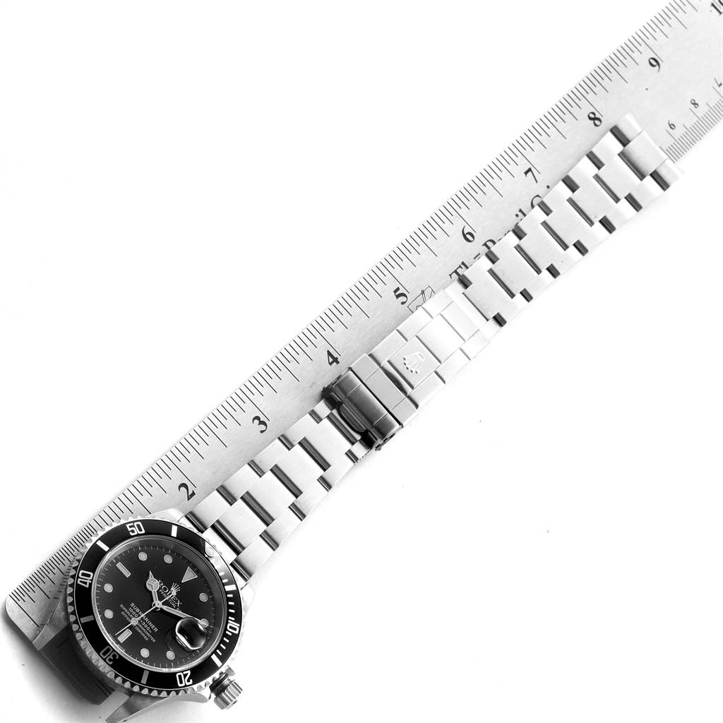 The image shows a top-down view of a Rolex Submariner 16610 Men
s Stainless Steel Black Dial 16610 Men
s Stainless Steel Black Dial watch with its band extended along a ruler for measurement.