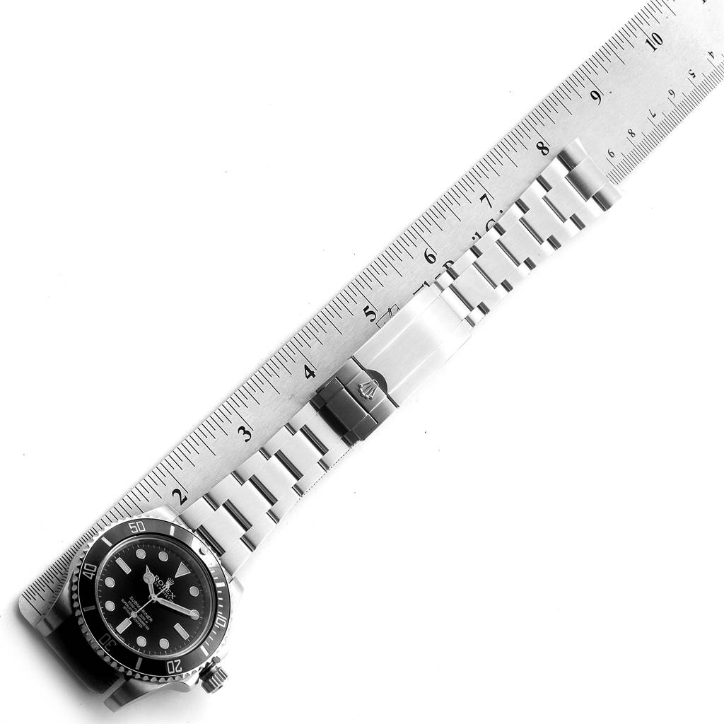 The image shows a Rolex Submariner 114060 Men
s Stainless Steel Black Dial 114060 Men
s Stainless Steel Black Dial watch laid flat with its bracelet extended next to a straight ruler.