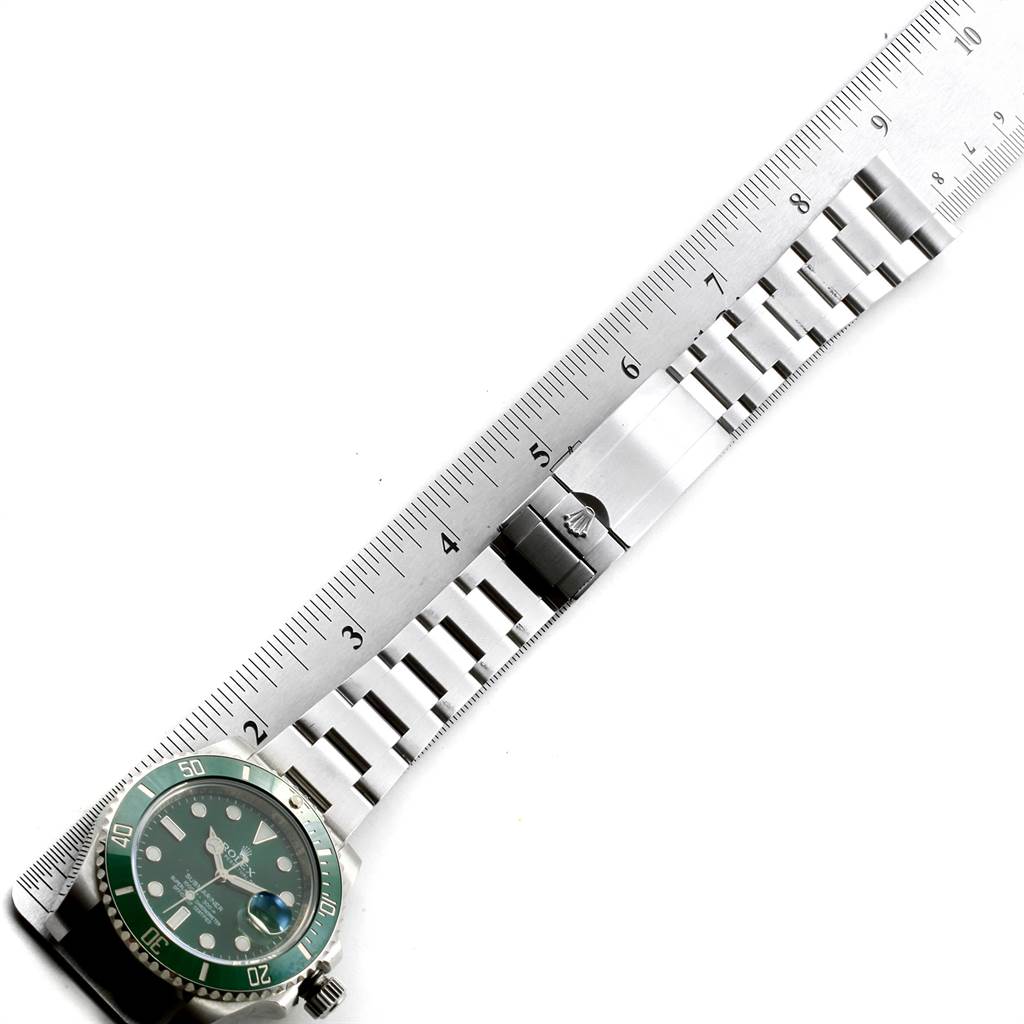 The image shows a Rolex Submariner 116610LV Men
s Stainless Steel Green Dial 116610LV Men
s Stainless Steel Green Dial watch with a green bezel, partially measured against a ruler, highlighting its bracelet.