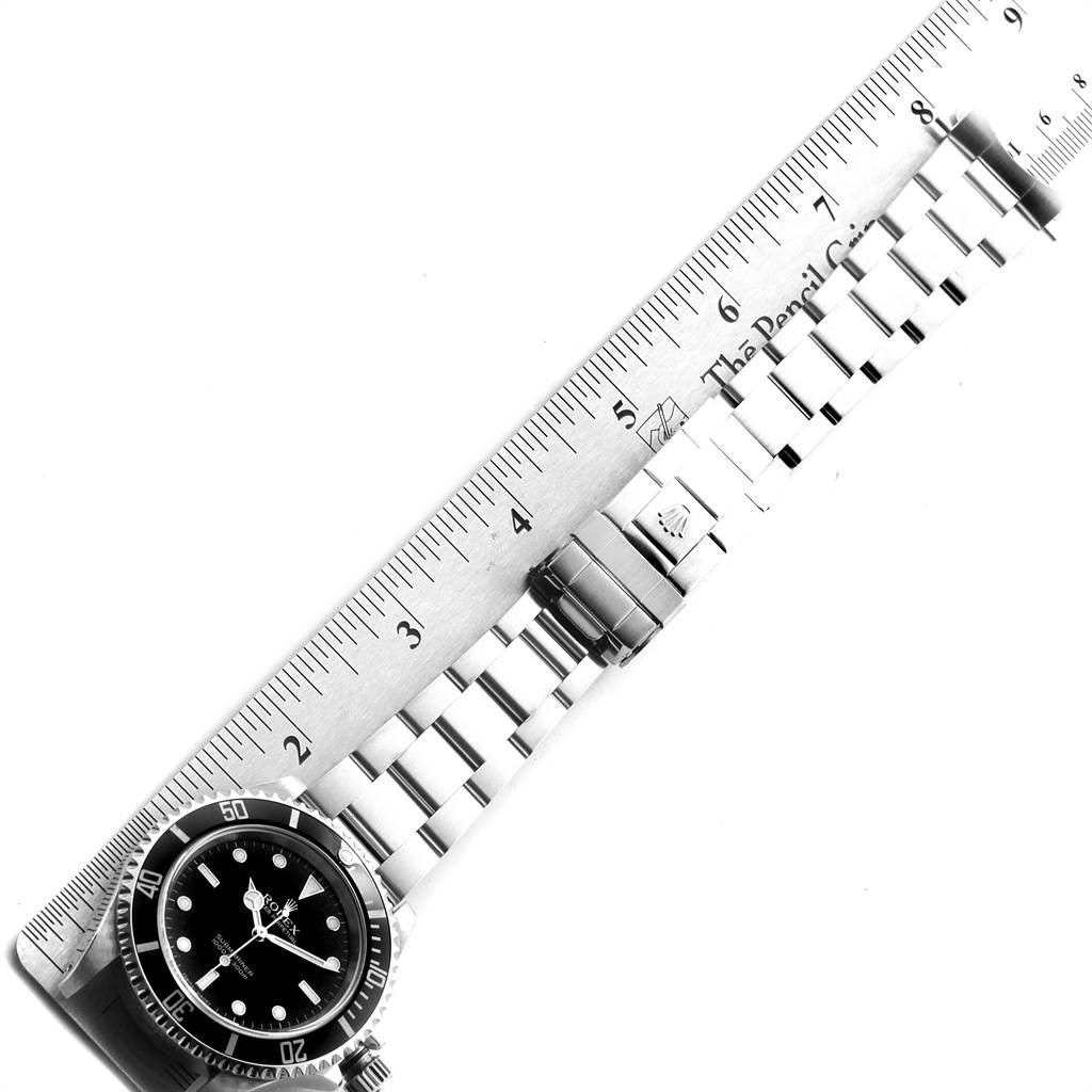This image shows a top-down view of a Rolex Submariner 14060 Men
s Stainless Steel Black Dial 14060 Men
s Stainless Steel Black Dial watch with its metal band measured against a ruler.