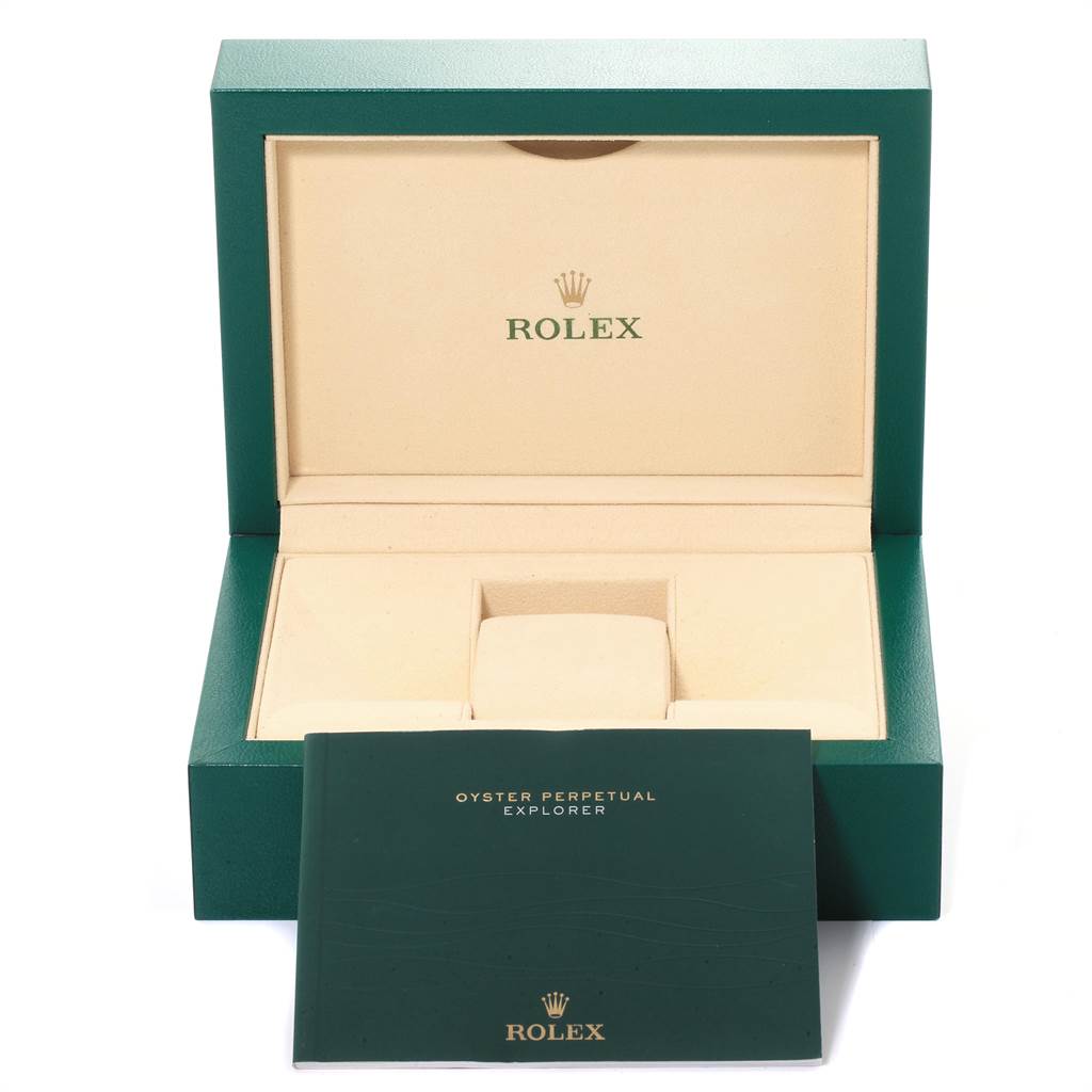 The image shows an open Rolex watch box with a cushion inside and a green booklet labeled "Oyster Perpetual Explorer" in front.
