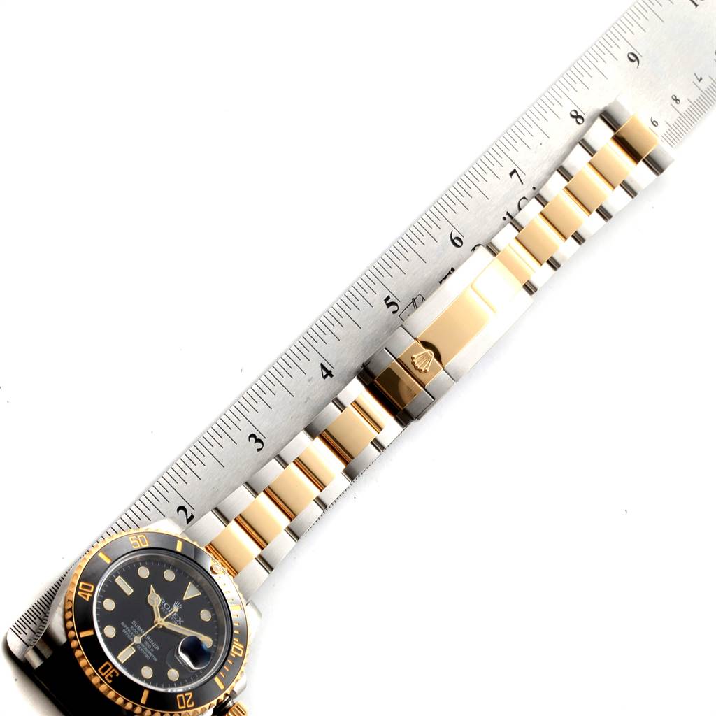 The image shows the face and band of a Rolex Submariner 116613 Men's Steel and Gold (two tone) Black Dial 116613 Men's Steel and Gold (two tone) Black Dial watch, aligned with a ruler for measurement.