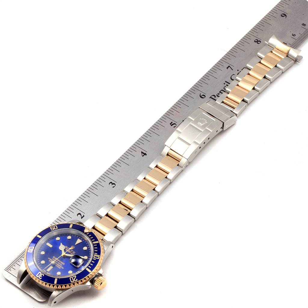 The Rolex Submariner 16613 Men
s Steel and Gold (two tone) Blue Dial 16613 Men
s Steel and Gold (two tone) Blue Dial watch is shown from an angle highlighting the face, bezel, and the full length of the two-tone bracelet.