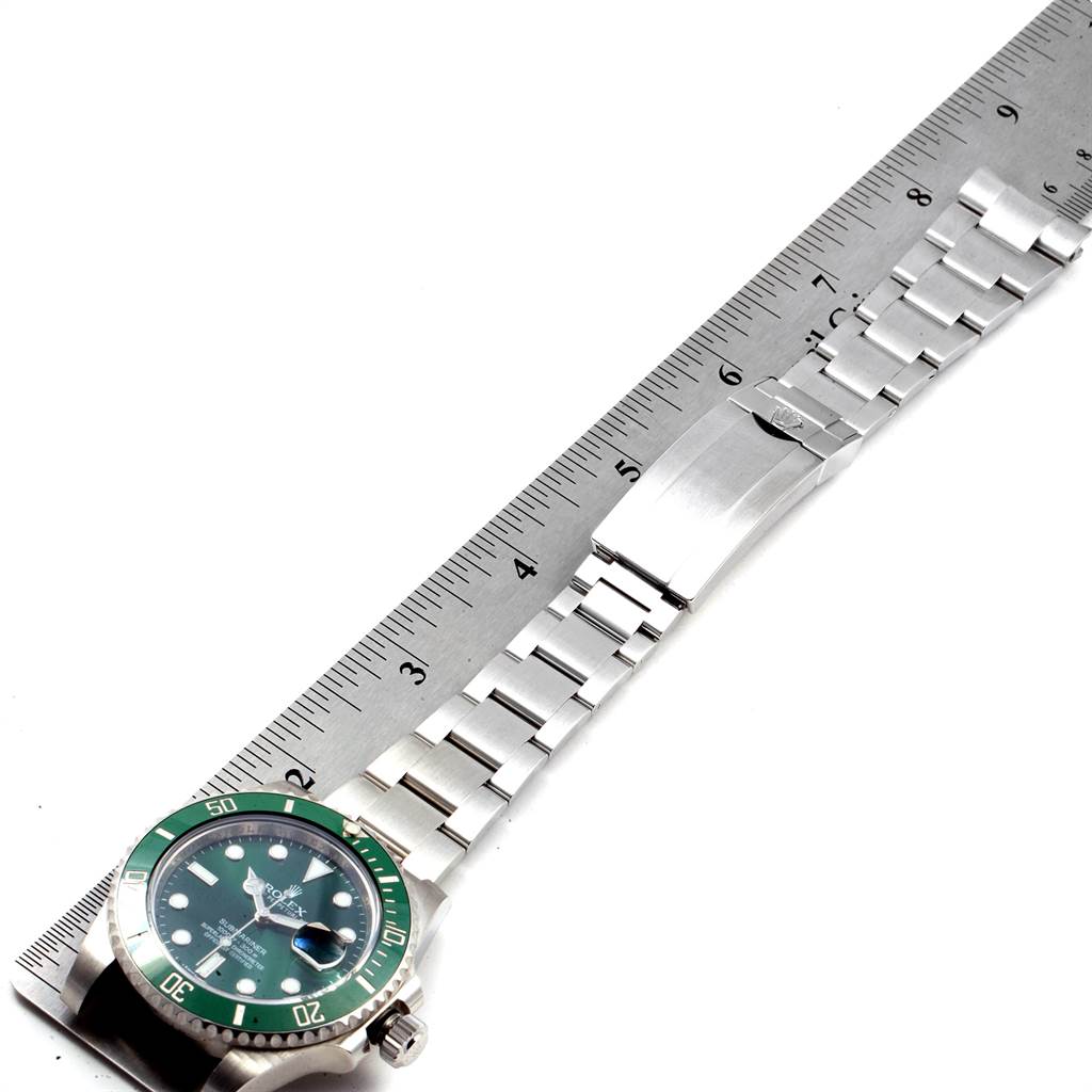 The image shows a Rolex Submariner 116610LV Men
s Stainless Steel Green Dial 116610LV Men
s Stainless Steel Green Dial watch laid flat, displaying the dial, bezel, and bracelet with a ruler for scale.