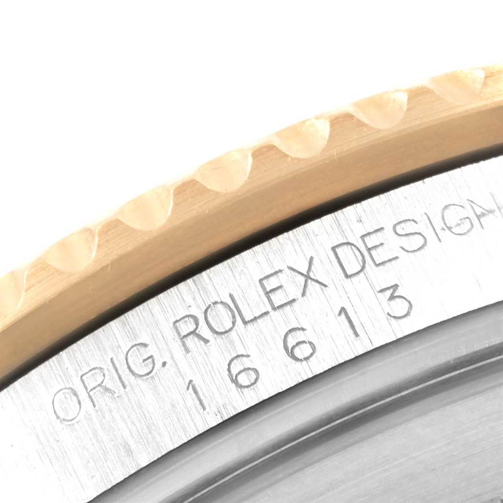 The image shows a close-up of the case and bezel edge of the Rolex Submariner 16613 Men
s Steel and Gold (two tone) Blue Dial 16613 Men
s Steel and Gold (two tone) Blue Dial, highlighting its model number and "ROLEX DESIGN" inscription.