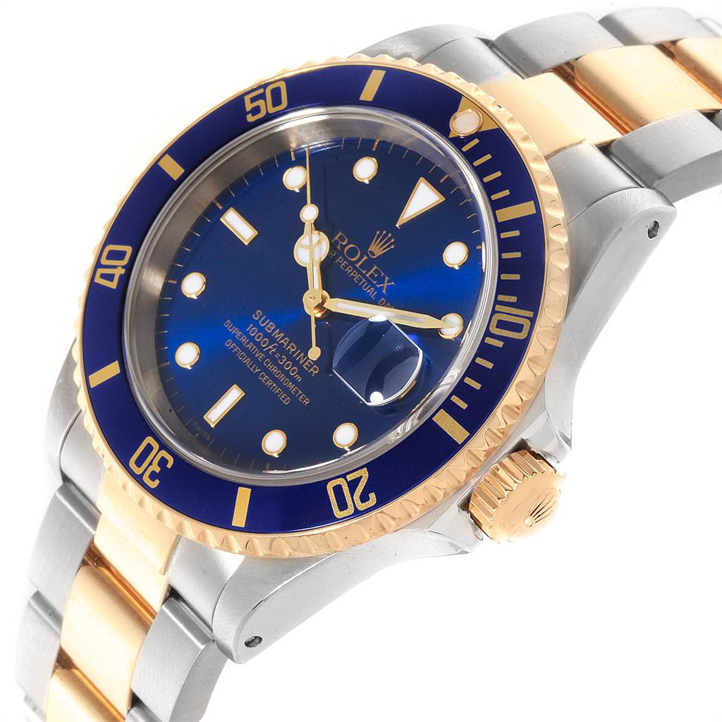 The image shows a close-up of the Rolex Submariner 16613 Men
s Steel and Gold (two tone) Blue Dial 16613 Men
s Steel and Gold (two tone) Blue Dial watch, highlighting its blue dial, bezel, and two-tone bracelet at an angle.