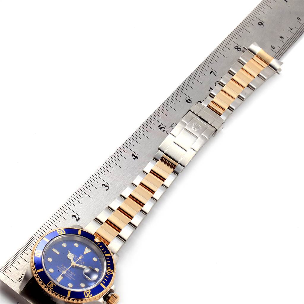 The image shows a Rolex Submariner 16613 Men
s Steel and Gold (two tone) Blue Dial 16613 Men
s Steel and Gold (two tone) Blue Dial watch face, bracelet, and clasp, measured against a ruler.