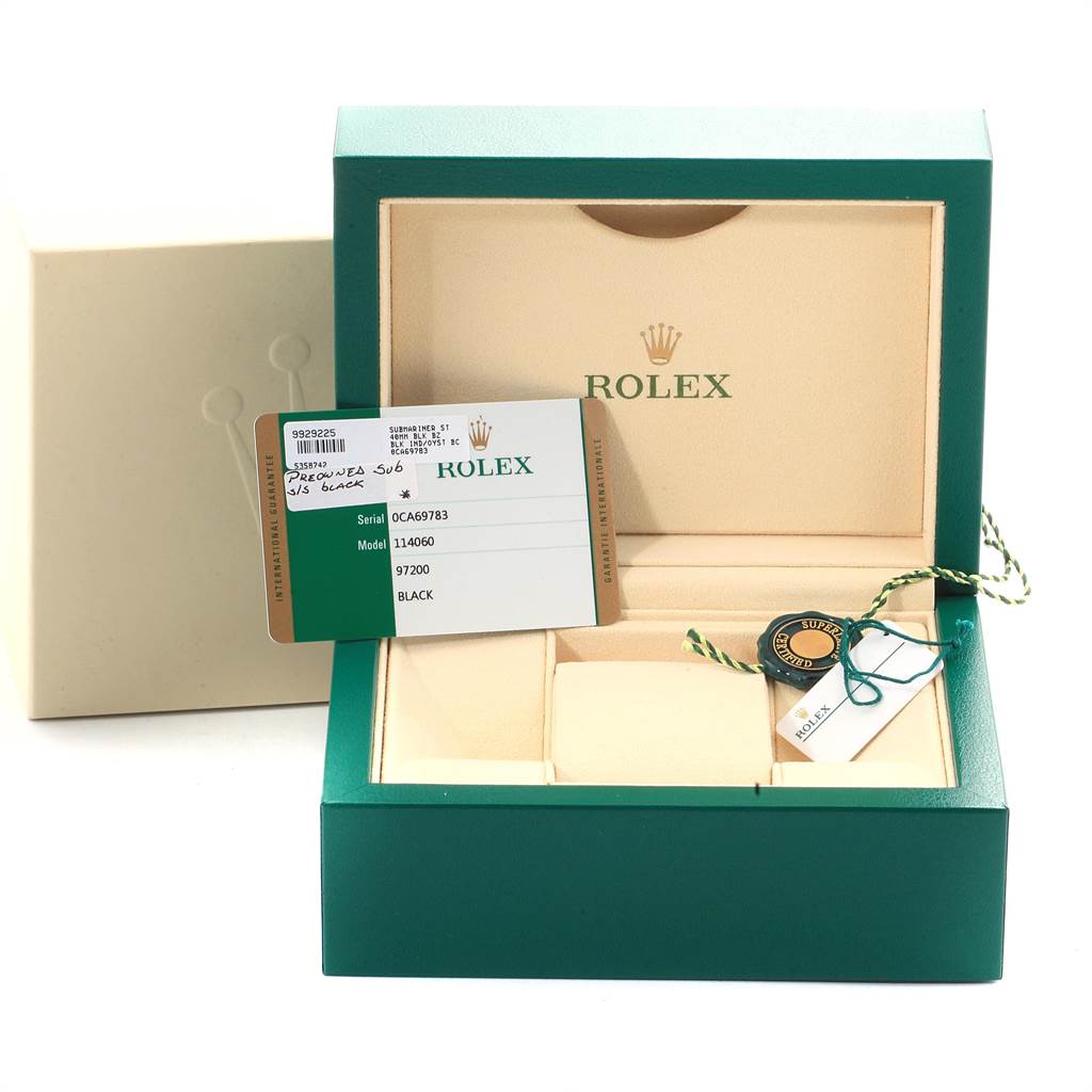 The image shows an open green Rolex box for the Submariner model with the warranty card and tags displayed.