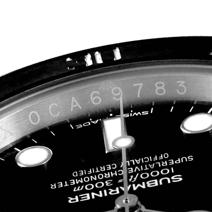 The image shows a close-up of the dial and serial number of a Rolex Submariner 114060 Men
s Stainless Steel Black Dial 114060 Men
s Stainless Steel Black Dial watch, specifically highlighting part of the bezel and markers.