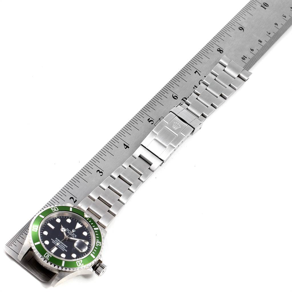 The image shows a side angle of a Rolex Submariner 16610LV Men
s Stainless Steel Black Dial 16610LV Men
s Stainless Steel Black Dial watch with its metal bracelet extended alongside a ruler.