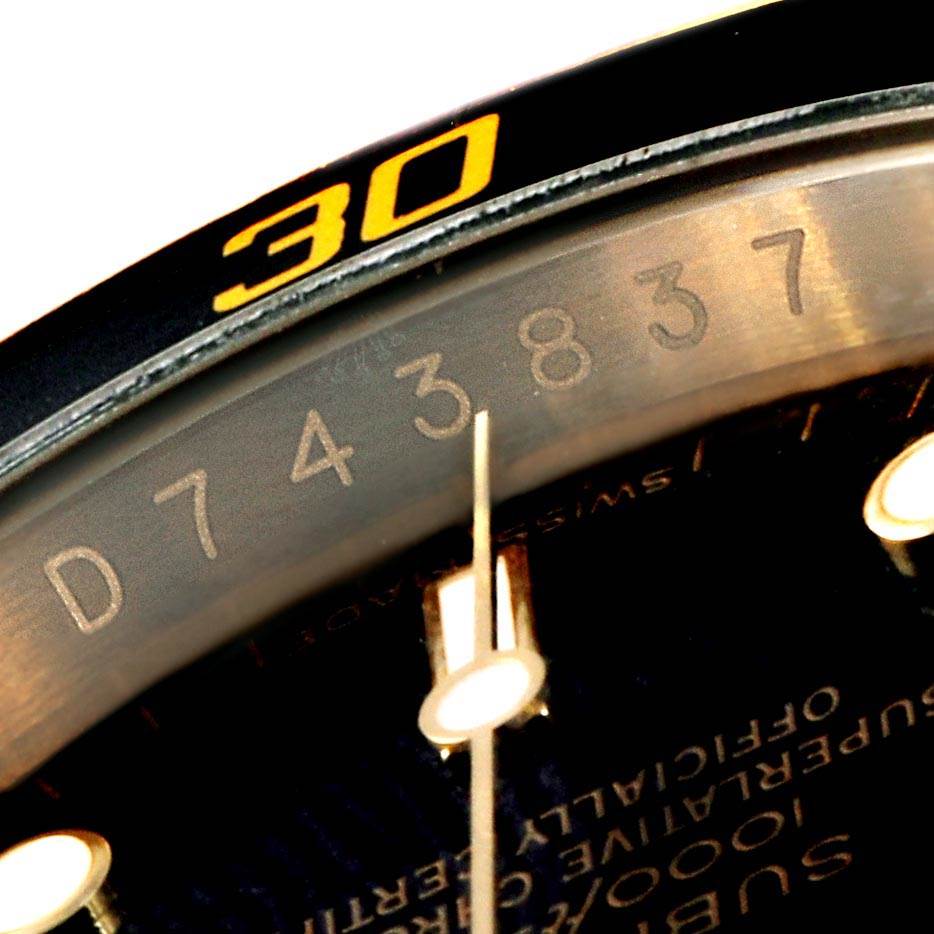 This close-up image of a Rolex Submariner 16618 Men
s Yellow Gold Black Dial 16618 Men
s Yellow Gold Black Dial watch shows part of the bezel, indices, and a portion of the serial number.