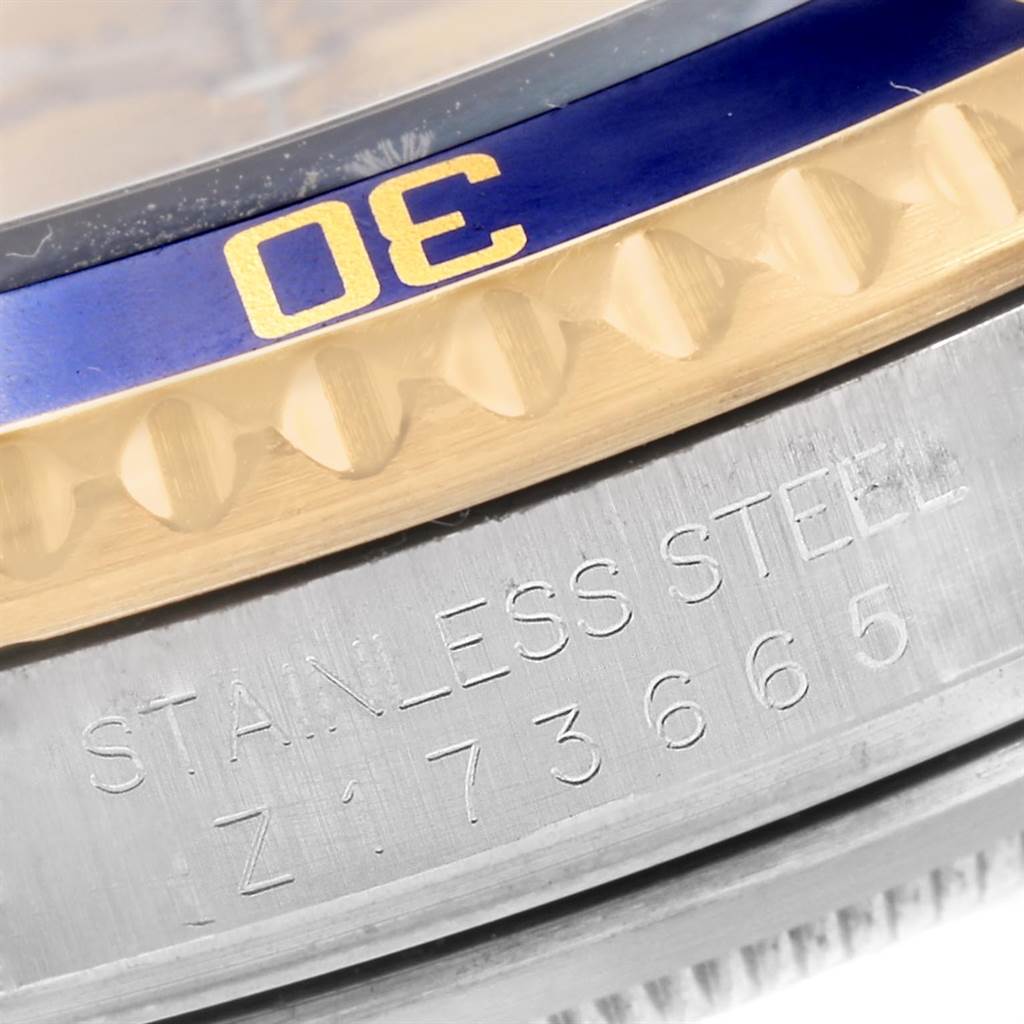 The image shows a close-up of the stainless steel case and blue bezel of a Rolex Submariner 16613 Men's Steel and Gold (two tone) Champagne Dial 16613 Men's Steel and Gold (two tone) Champagne Dial model, featuring the inscription "STAINLESS STEEL."