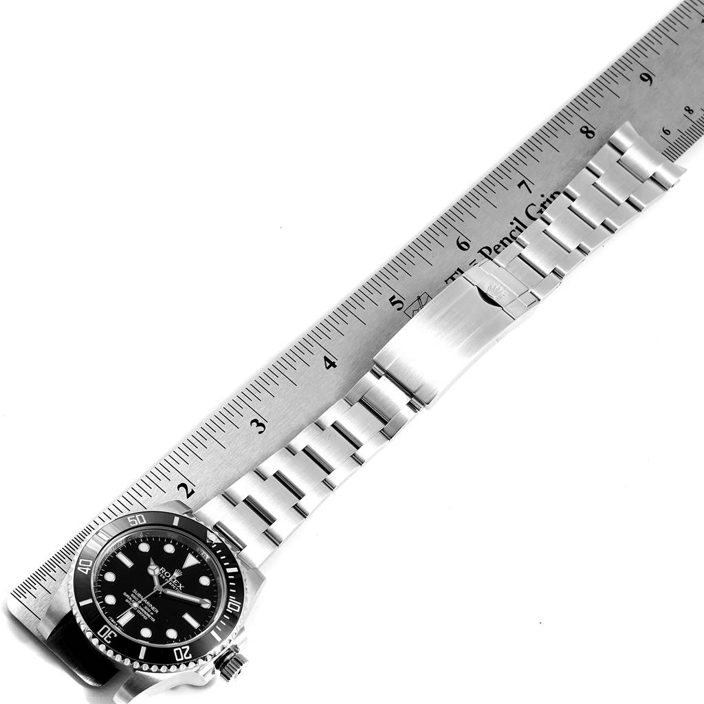 The image shows the Rolex Submariner 114060 Men's Stainless Steel Black Dial 114060 Men's Stainless Steel Black Dial watch laid flat next to a ruler, displaying its face, bracelet, and clasp.