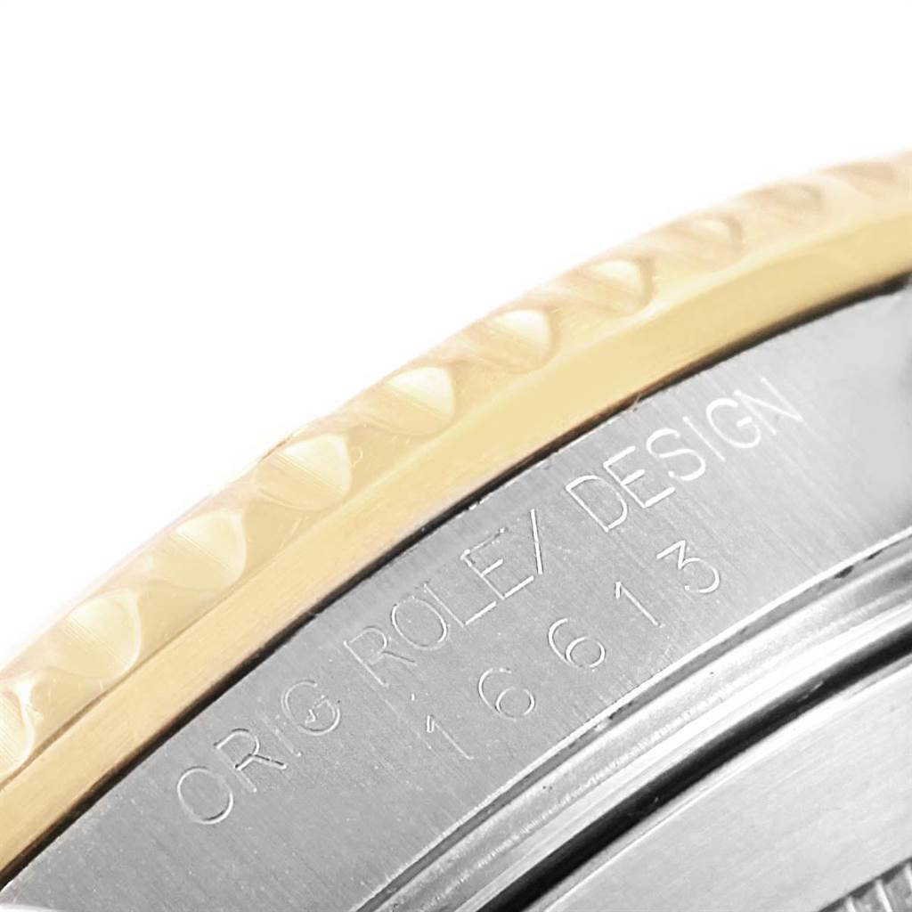 The close-up image shows the side of a Rolex Submariner 16613 Men
s Steel and Gold (two tone) Blue Dial 16613 Men
s Steel and Gold (two tone) Blue Dial watch case, emphasizing the etched model number and part of the bezel.