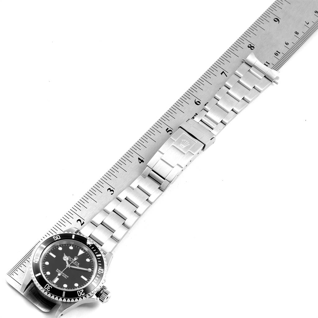 The image shows a Rolex Submariner 14060 Men's Stainless Steel Black Dial 14060 Men's Stainless Steel Black Dial watch laid flat with a ruler, displaying the watch face, crown, and bracelet.