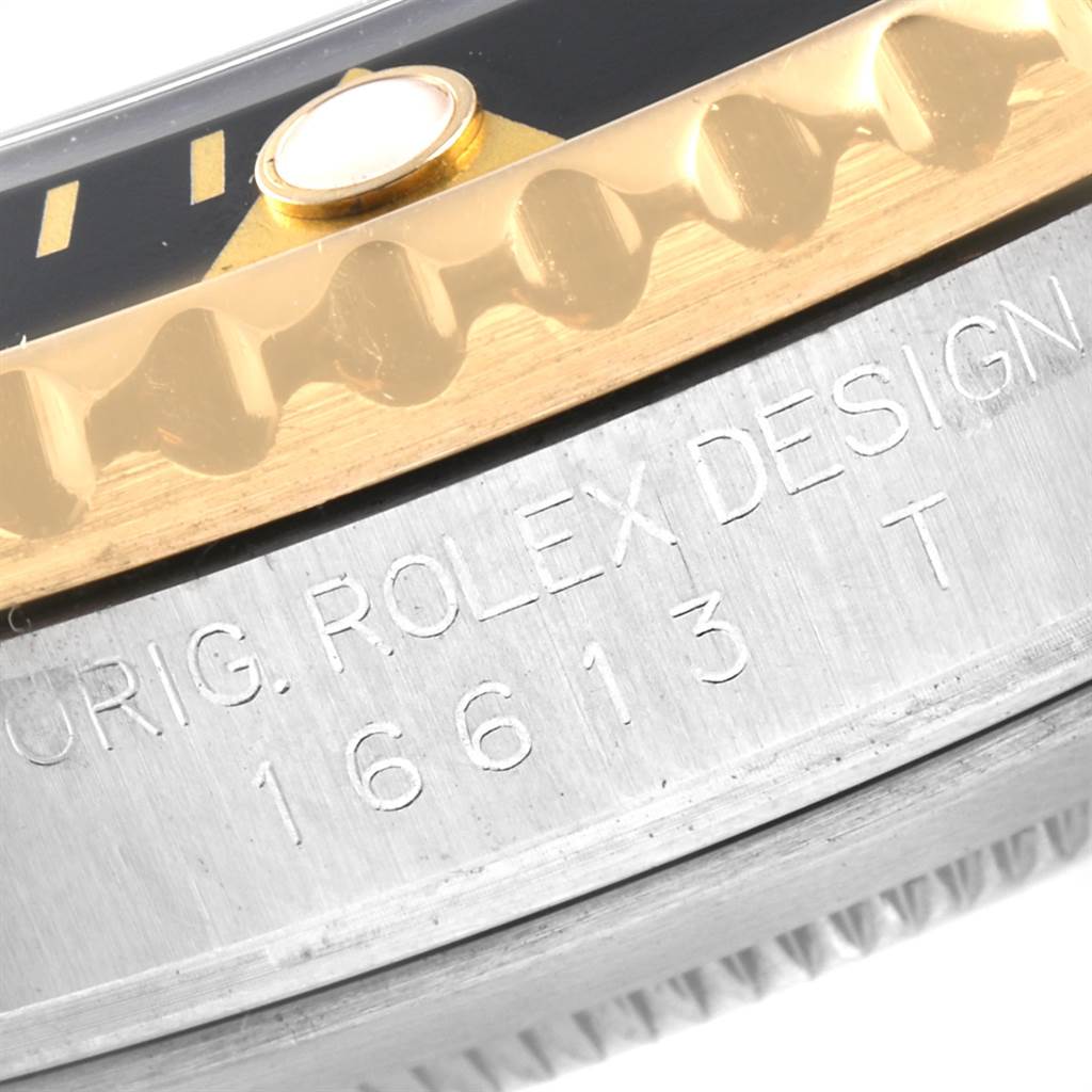 The image shows a close-up of the bezel and case of a Rolex Submariner 16613 Men
s Steel and Gold (two tone) Black Dial 16613 Men
s Steel and Gold (two tone) Black Dial watch, highlighting the engraving and part of the bezel.