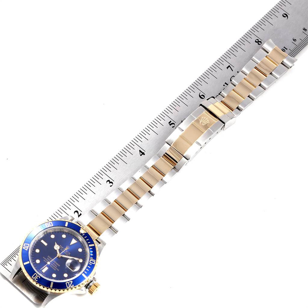 The image shows a Rolex Submariner 16613 Men
s Steel and Gold (two tone) Blue Dial 16613 Men
s Steel and Gold (two tone) Blue Dial watch laid flat from an overhead angle, alongside a measuring ruler.