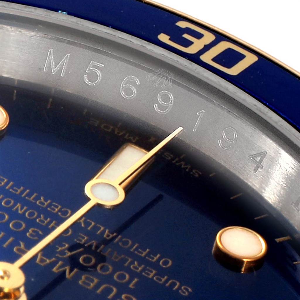 The image shows a close-up of the dial and bezel of a Rolex Submariner 16613 Men
s Steel and Gold (two tone) Blue Dial 16613 Men
s Steel and Gold (two tone) Blue Dial watch, highlighting the serial number and minute hand.