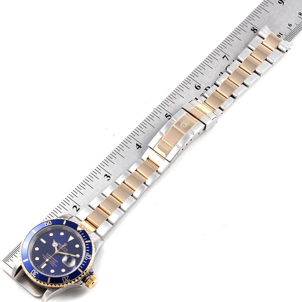 The Rolex Submariner 16613 Men
s Steel and Gold (two tone) Blue Dial 16613 Men
s Steel and Gold (two tone) Blue Dial watch is shown from a top view, with a metal ruler indicating the length of its bracelet.