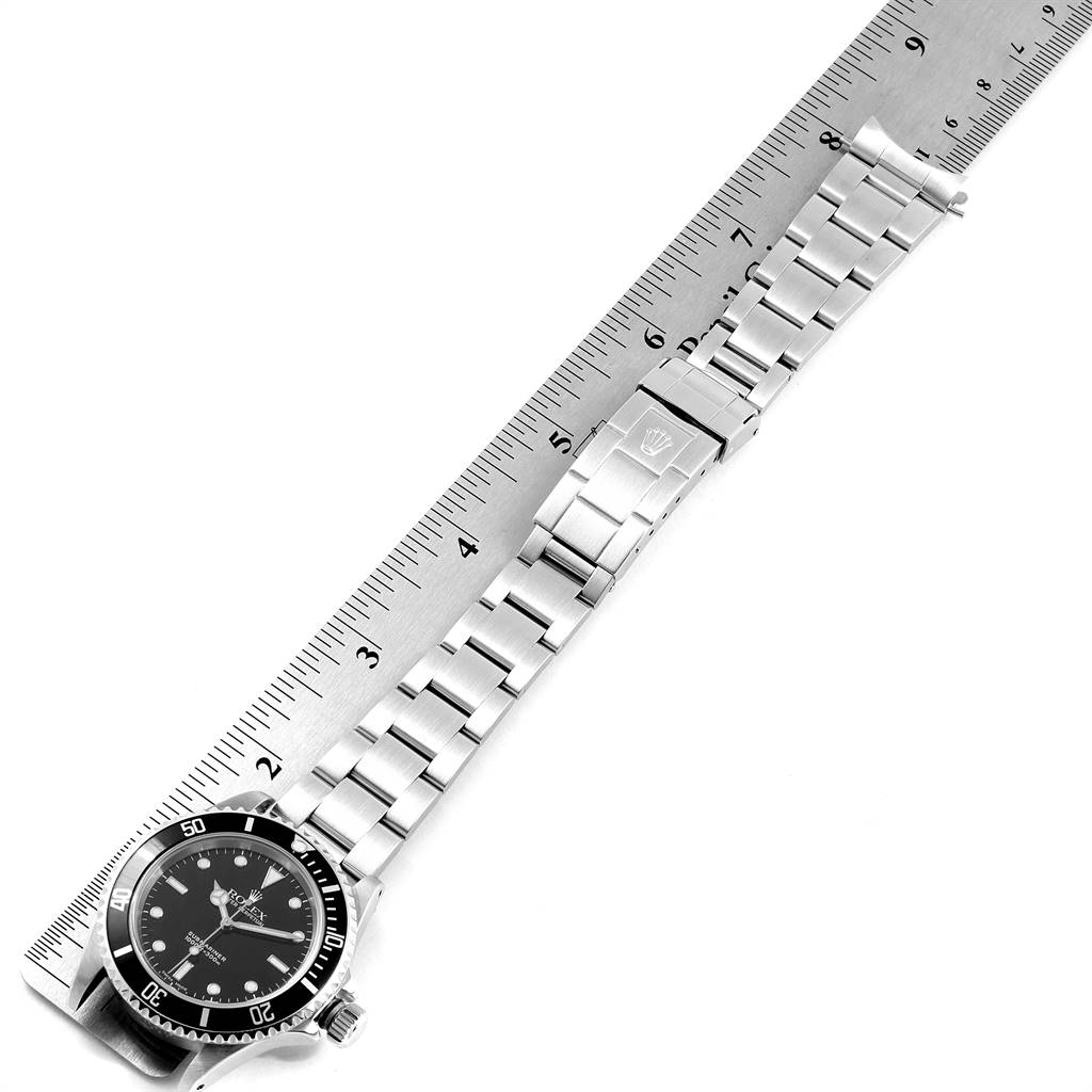 The image shows a Rolex Submariner 14060 Men's Stainless Steel Black Dial 14060 Men's Stainless Steel Black Dial watch fully extended beside a ruler, displaying its face, bezel, and bracelet with clasp.
