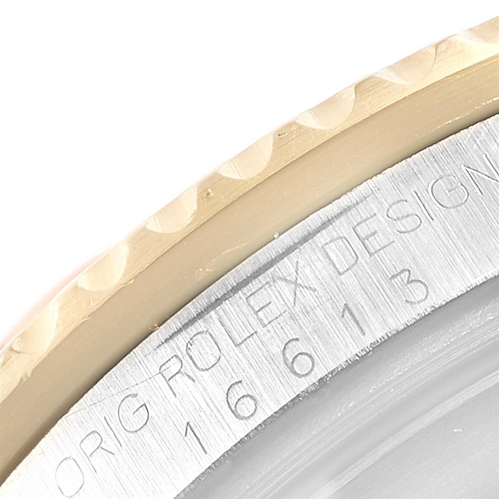 This close-up angle of the Rolex Submariner 16613 Men's Steel and Gold (two tone) Black Dial 16613 Men's Steel and Gold (two tone) Black Dial shows part of the bezel and engraved casing with the model number 16613.