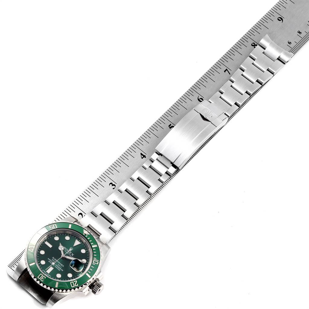 This image shows a Rolex Submariner 116610LV Men
s Stainless Steel Green Dial 116610LV Men
s Stainless Steel Green Dial watch laid flat, displaying both the watch face and the metal band beside a ruler for size reference.