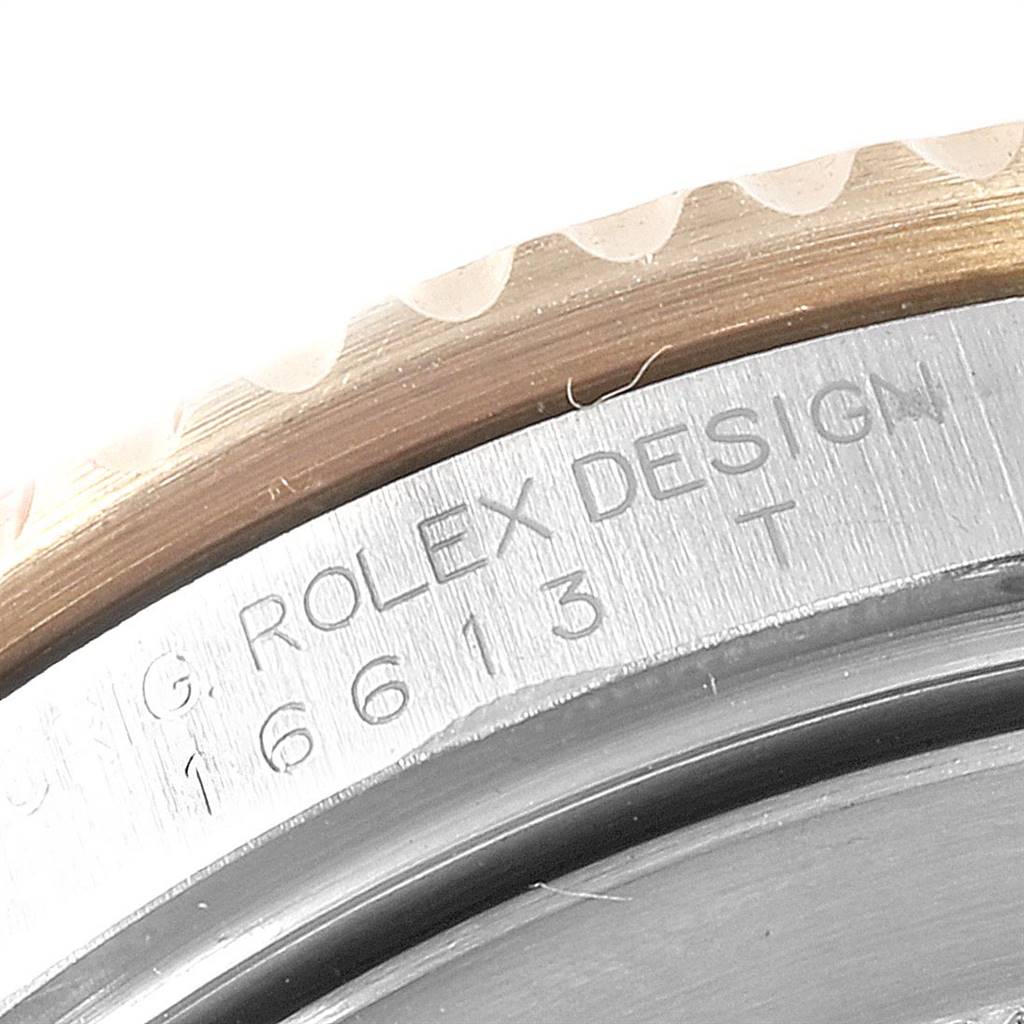Close-up of the engraved casing back edge of a Rolex Submariner 16613 Men's Steel and Gold (two tone) Blue Dial 16613 Men's Steel and Gold (two tone) Blue Dial watch, showing "Rolex Design" and model number 16613.