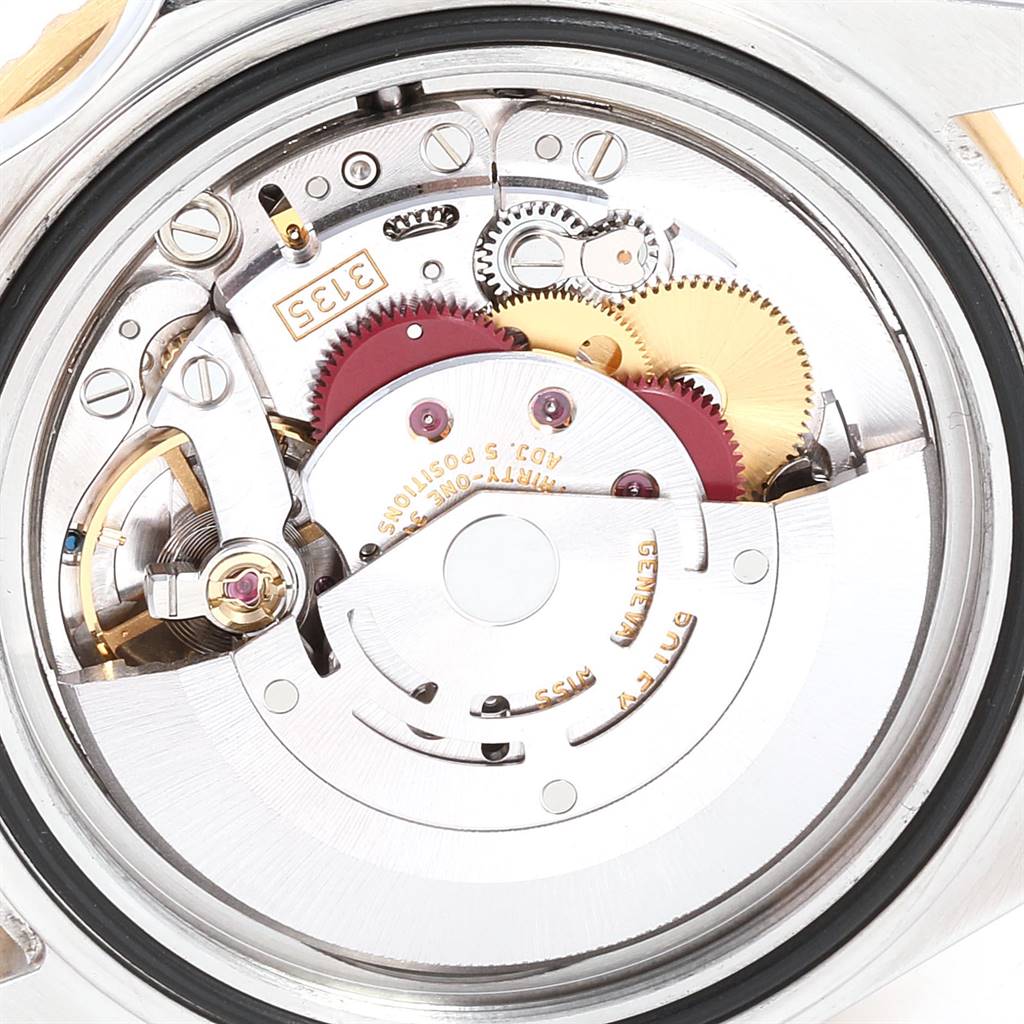 The image shows an internal view of the Rolex Submariner 16613 Men
s Steel and Gold (two tone) Blue Dial 16613 Men
s Steel and Gold (two tone) Blue Dial watch mechanism featuring gears and internal components.