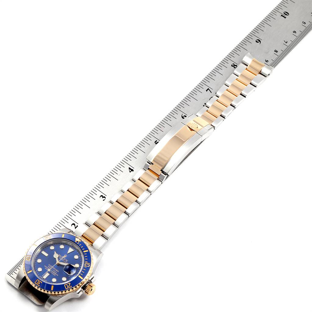 The image shows a top-down view of a Rolex Submariner 116613 Men's Steel and Gold (two tone) Blue Dial 116613 Men's Steel and Gold (two tone) Blue Dial watch, detailing the face, bezel, and entire bracelet beside a ruler for scale.