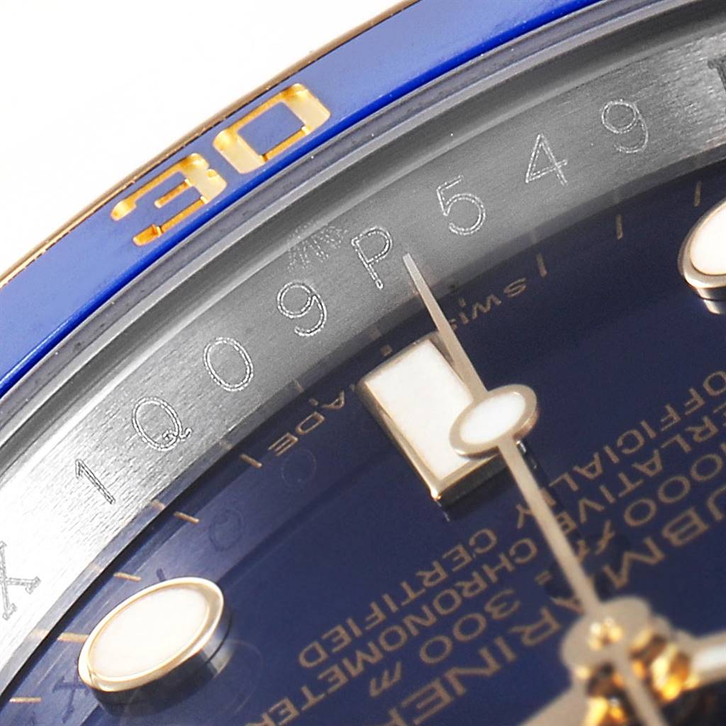 The image shows a close-up of the Rolex Submariner 116613 Men's Steel and Gold (two tone) Blue Dial 116613 Men's Steel and Gold (two tone) Blue Dial model's dial, bezel, and part of the serial number engraving.