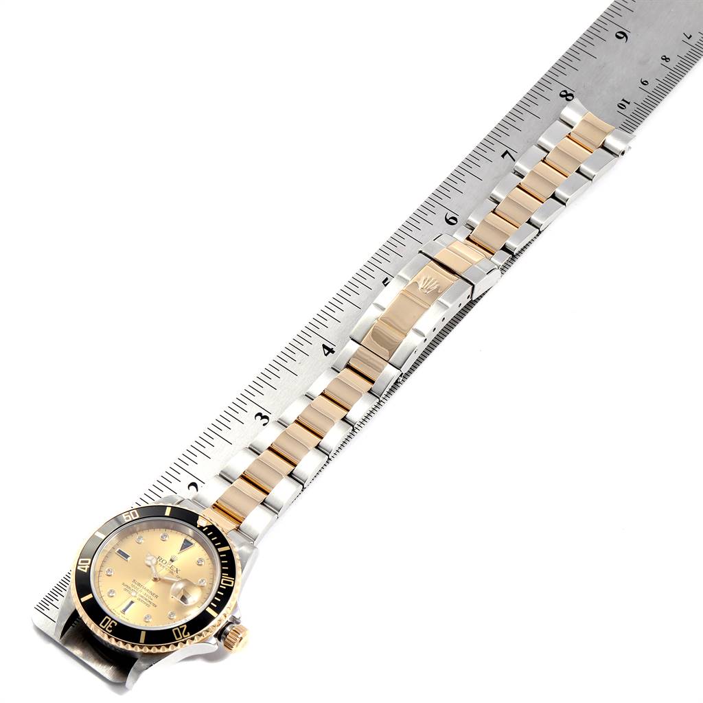 The image shows a Rolex Submariner 16613 Men's Steel and Gold (two tone) Champagne Dial 16613 Men's Steel and Gold (two tone) Champagne Dial watch laid flat with the full length of the band and the face visible against a ruler for measurement.