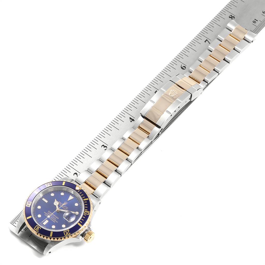 The image shows a Rolex Submariner 16613 Men
s Steel and Gold (two tone) Blue Dial 16613 Men
s Steel and Gold (two tone) Blue Dial watch lying flat, with its blue dial and two-tone bracelet measured against a ruler.