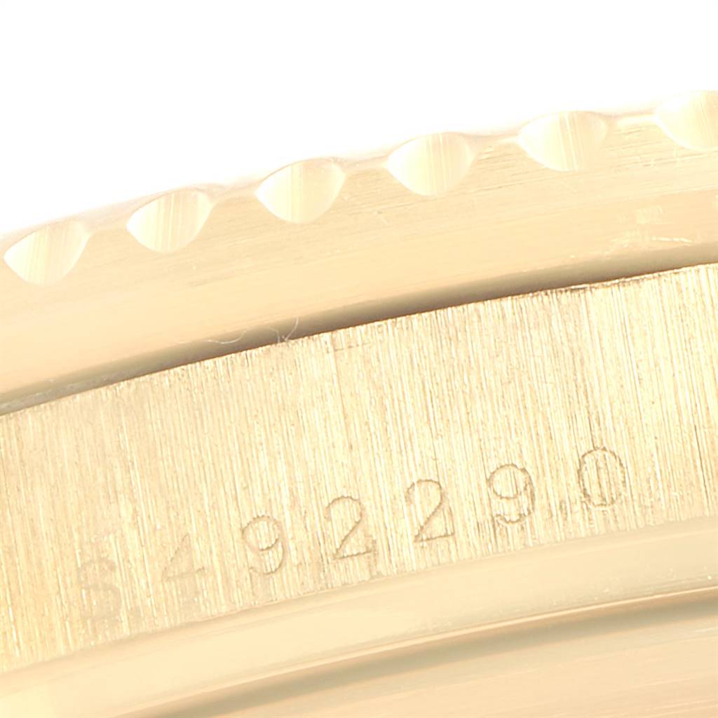 The image shows a close-up of the Rolex Submariner 16618 Men
s Yellow Gold Black Dial 16618 Men
s Yellow Gold Black Dial watch
s bezel edge and part of its engraved serial number.