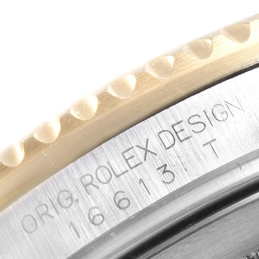 This close-up image of a Rolex Submariner 16613 Men
s Steel and Gold (two tone) Blue Dial 16613 Men
s Steel and Gold (two tone) Blue Dial watch shows the case side with engraved text and part of the bezel.