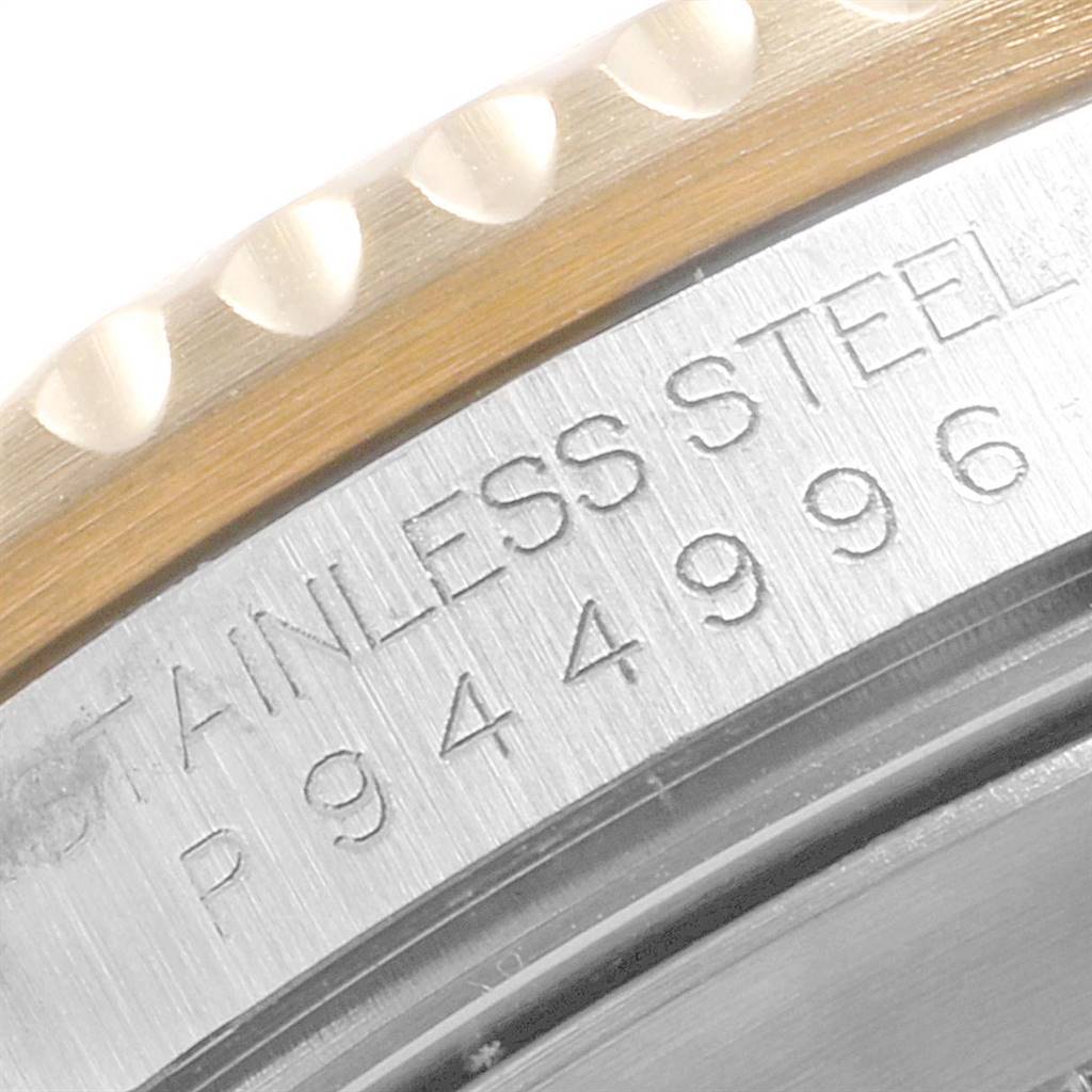 This close-up image shows part of the serial number and "STAINLESS STEEL" engraving on the side of the bezel of a Rolex Submariner 16613 Men
s Steel and Gold (two tone) Blue Dial 16613 Men
s Steel and Gold (two tone) Blue Dial watch.
