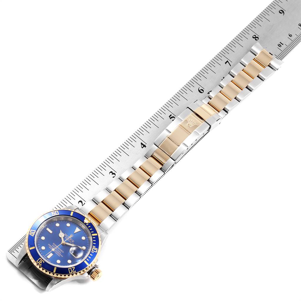 The image shows the Rolex Submariner 16613 Men
s Steel and Gold (two tone) Blue Dial 16613 Men
s Steel and Gold (two tone) Blue Dial watch laid flat with its face and bracelet measured against a ruler.