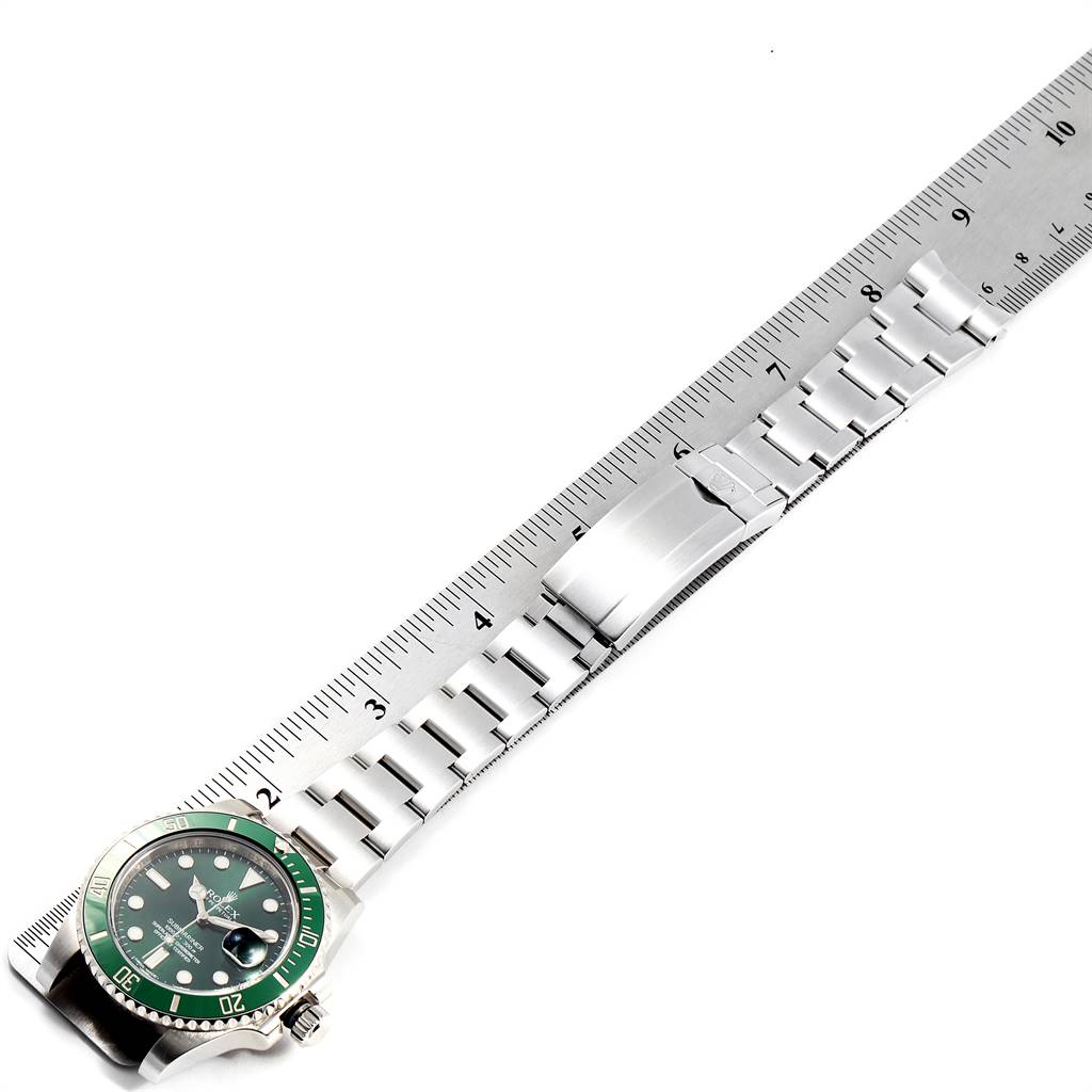 The image shows a Rolex Submariner 116610LV Men
s Stainless Steel Green Dial 116610LV Men
s Stainless Steel Green Dial watch laid flat next to a ruler, highlighting its metal bracelet and clasp.