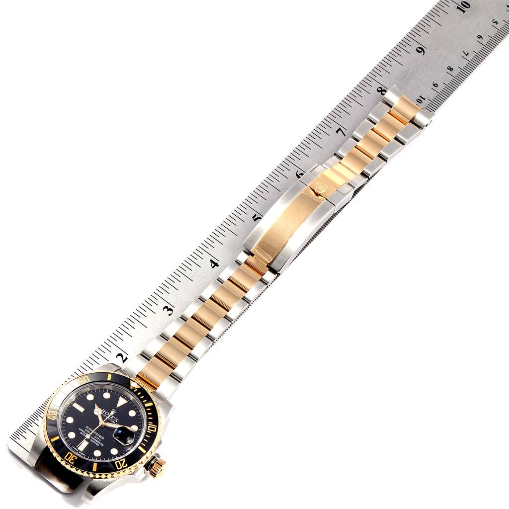 The image shows a Rolex Submariner 116613 Men's Steel and Gold (two tone) Black Dial 116613 Men's Steel and Gold (two tone) Black Dial watch laid flat, highlighting its bracelet and clasp next to a ruler for scale.