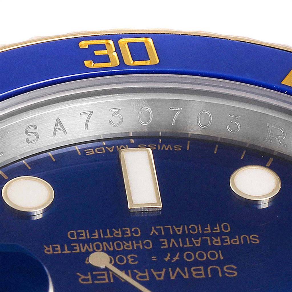 This close-up angle of the Rolex Submariner 116613 Men
s Steel and Gold (two tone) Blue Dial 116613 Men
s Steel and Gold (two tone) Blue Dial watch shows the blue bezel with the 30-minute mark, part of the dial, and serial engraving.