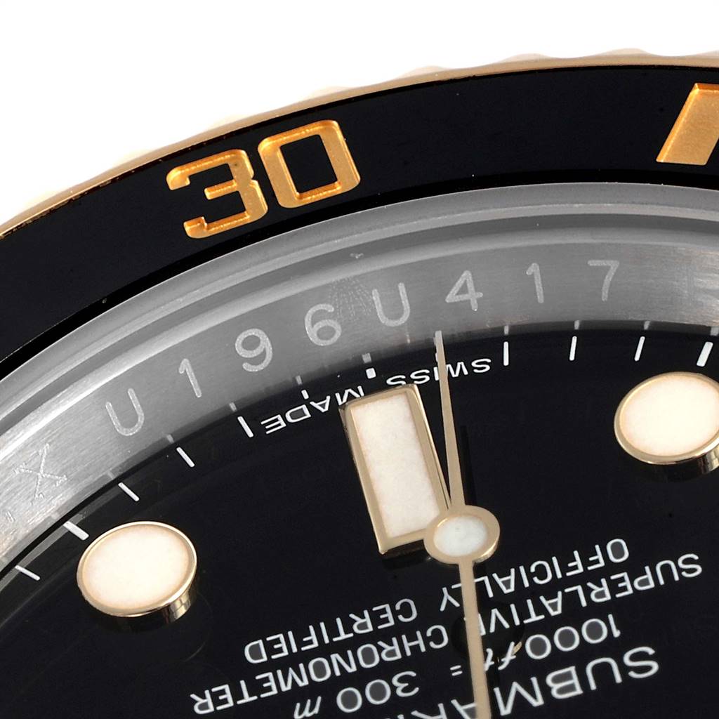 This close-up image of a Rolex Submariner 116613 Men
s Steel and Gold (two tone) Black Dial 116613 Men
s Steel and Gold (two tone) Black Dial watch shows part of the bezel, dial, and chapter ring with the serial number.