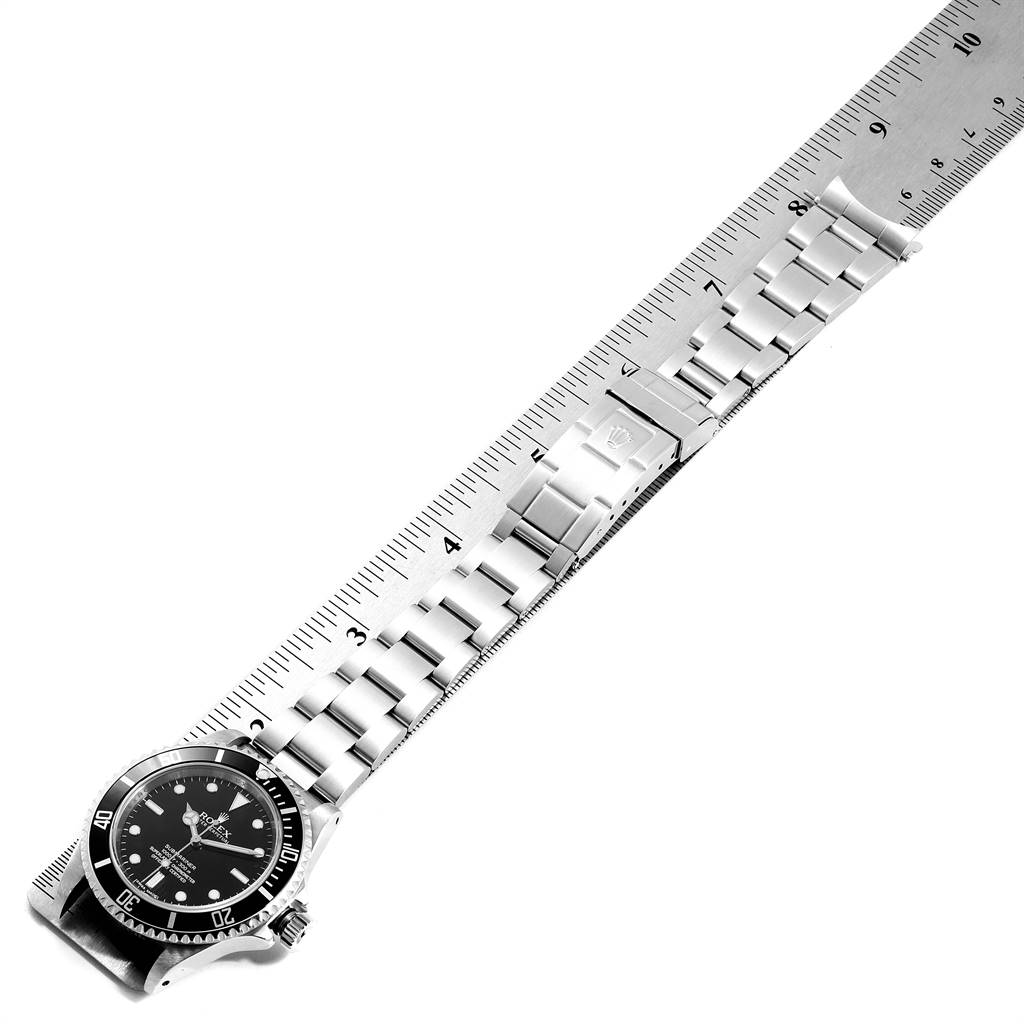 The image shows a Rolex Submariner 14060 Men
s Stainless Steel Black Dial 14060 Men
s Stainless Steel Black Dial watch laid flat next to a ruler, displaying the watch face and full length of the bracelet.