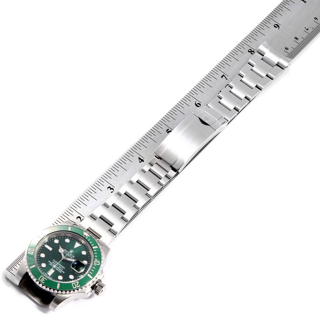 The image shows a Rolex Submariner 116610LV Men
s Stainless Steel Green Dial 116610LV Men
s Stainless Steel Green Dial watch laid flat against a ruler, displaying the face, bezel, and full metal bracelet.